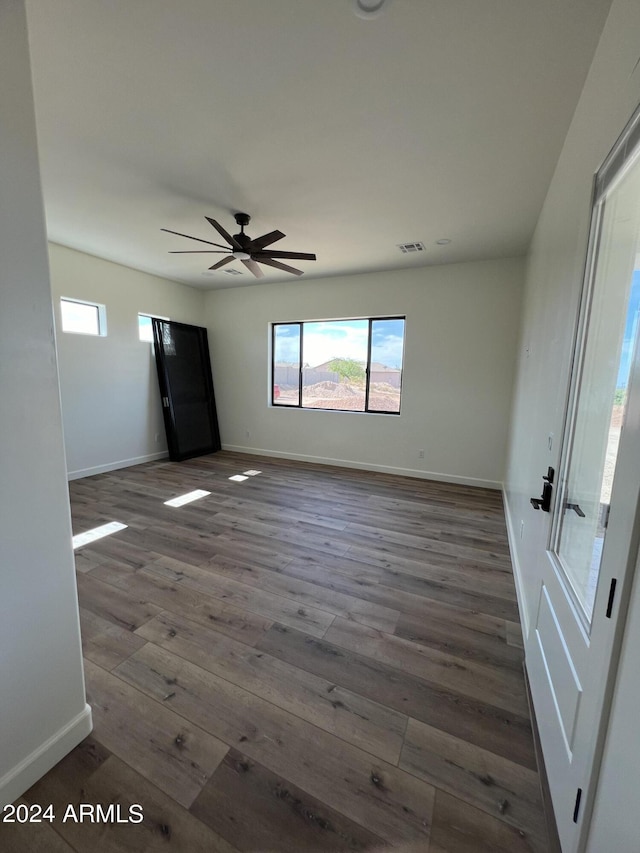 empty room with dark hardwood / wood-style floors and ceiling fan