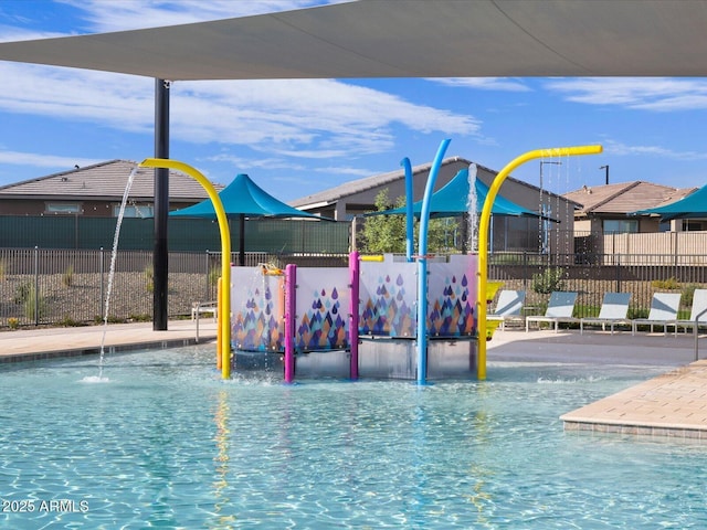 view of swimming pool featuring playground community and fence