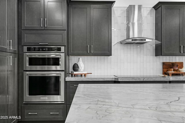 kitchen featuring backsplash, black electric stovetop, light stone countertops, stainless steel double oven, and wall chimney exhaust hood