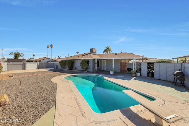 view of pool featuring cooling unit, a patio, and a diving board