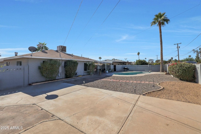 view of front of property featuring cooling unit, a fenced in pool, and a patio