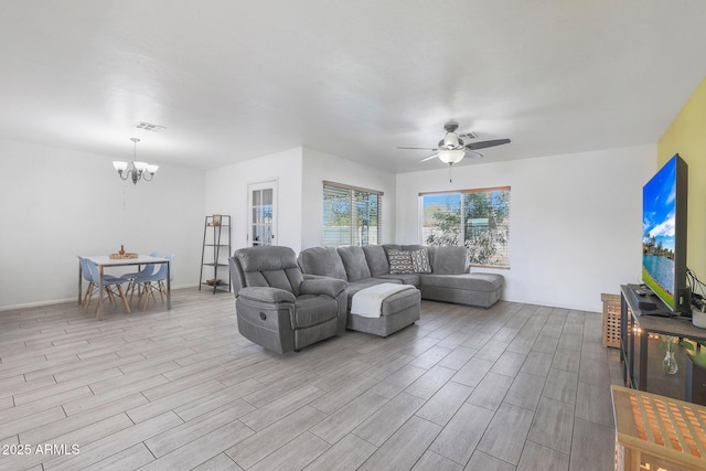 living room with ceiling fan with notable chandelier and light hardwood / wood-style floors