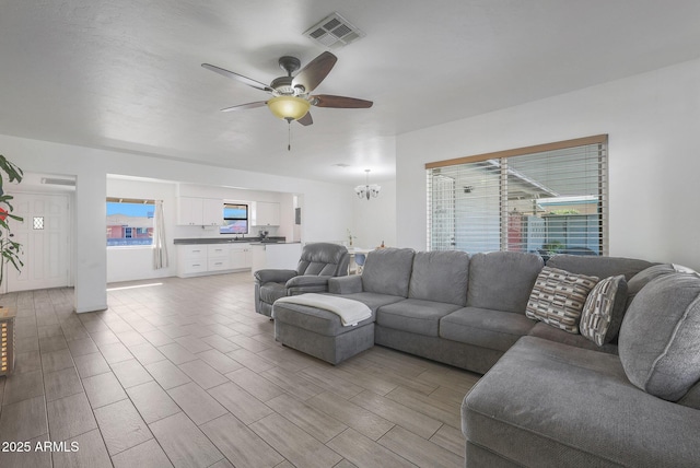 living room with ceiling fan with notable chandelier