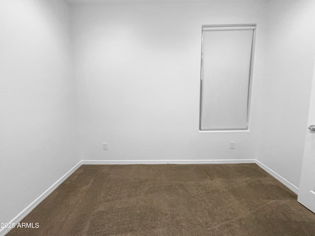 empty room featuring baseboards and dark colored carpet