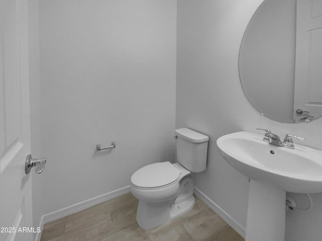 bathroom with toilet, baseboards, and a sink