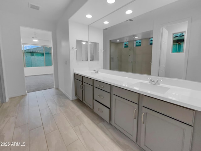 bathroom featuring double vanity, visible vents, a shower stall, and a sink