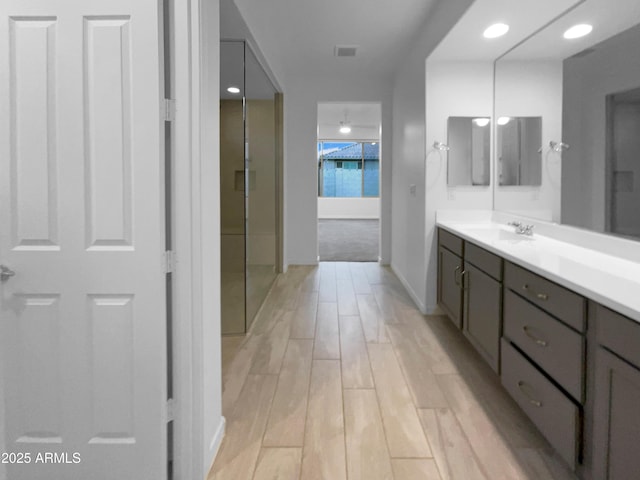 bathroom with a shower, wood finished floors, and vanity