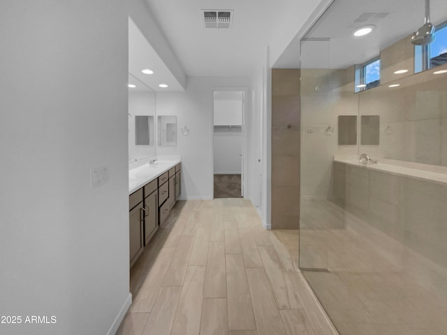 full bath featuring vanity, visible vents, wood tiled floor, a spacious closet, and a walk in shower