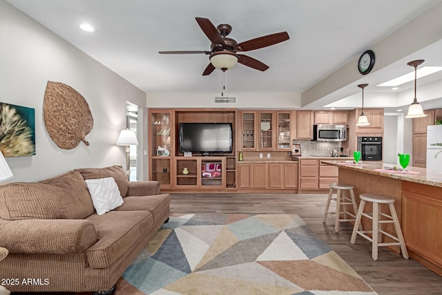 living area featuring recessed lighting, visible vents, light wood-style flooring, and a ceiling fan