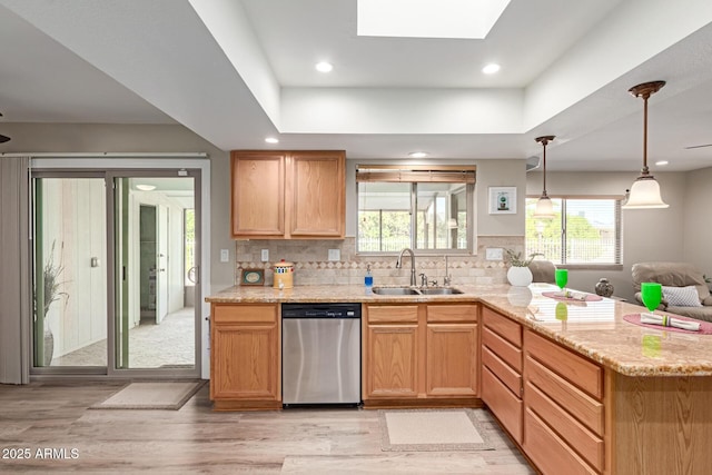 kitchen featuring light stone countertops, a peninsula, a sink, dishwasher, and tasteful backsplash