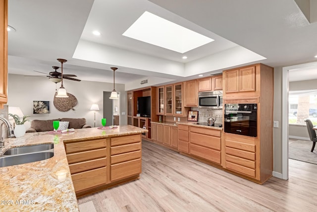 kitchen with black appliances, backsplash, a raised ceiling, and a sink