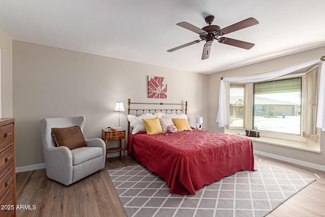 bedroom featuring light wood-style flooring, a ceiling fan, and baseboards