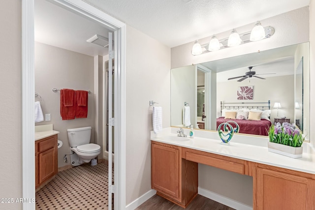 ensuite bathroom featuring baseboards, toilet, vanity, ensuite bath, and a ceiling fan