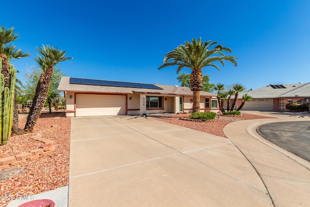 ranch-style home with stucco siding, roof mounted solar panels, a garage, and concrete driveway