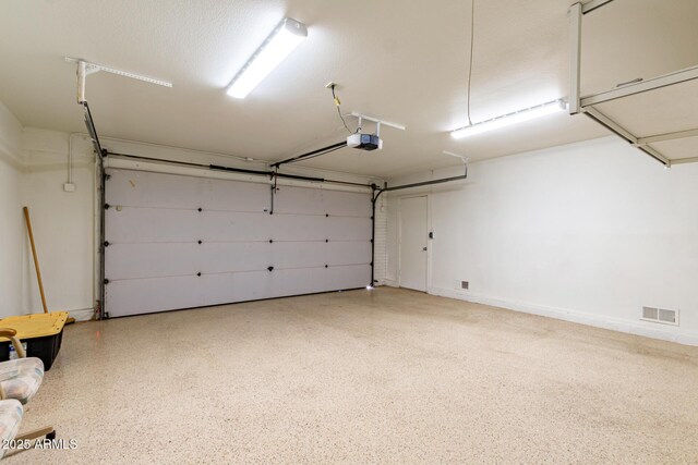 garage featuring visible vents, a garage door opener, and baseboards