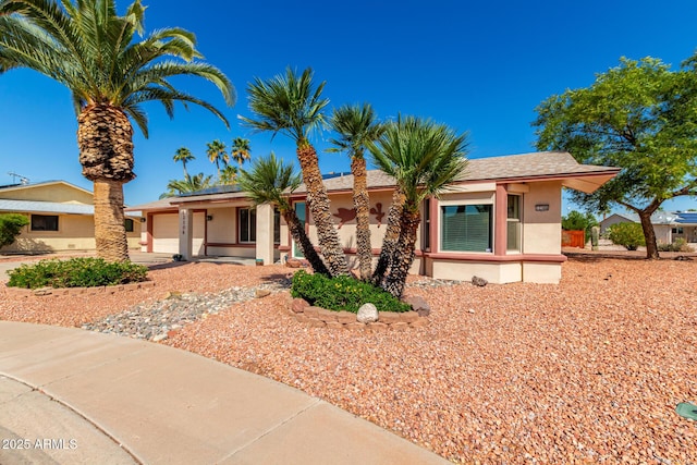 view of front of home featuring a garage, roof mounted solar panels, and stucco siding