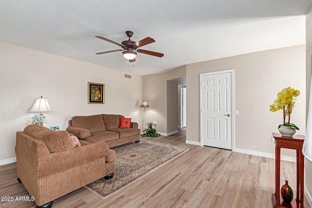 living room featuring visible vents, baseboards, and light wood finished floors