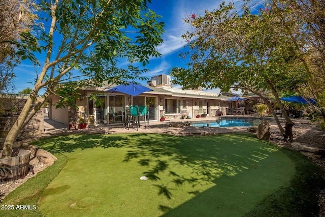 rear view of house featuring stone siding, a patio area, and an outdoor pool