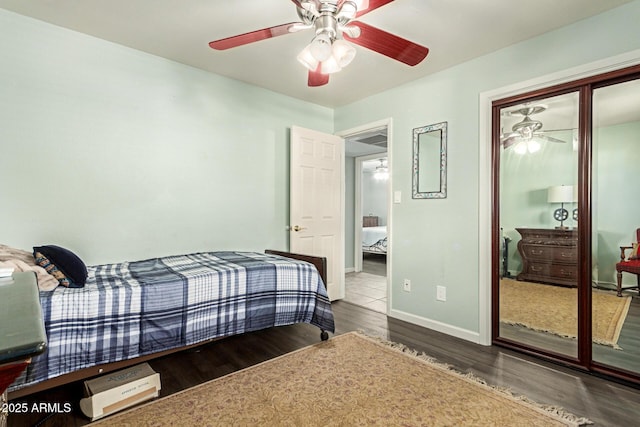 bedroom featuring ceiling fan, a closet, wood finished floors, and baseboards