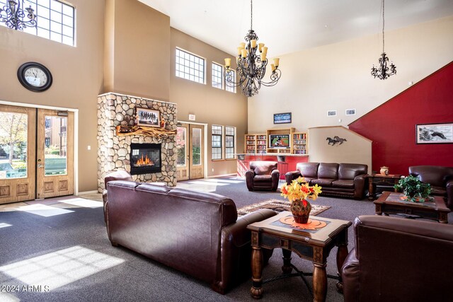 living room featuring a chandelier, carpet floors, a stone fireplace, and a high ceiling