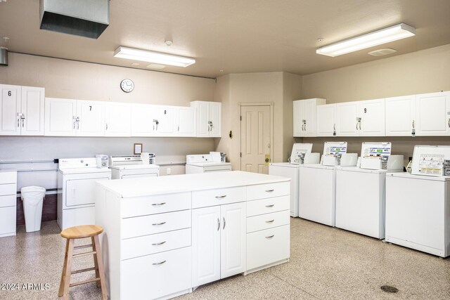 kitchen featuring a center island, washing machine and dryer, a breakfast bar area, and white cabinetry