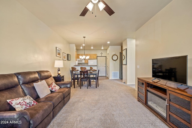 carpeted living room with ceiling fan with notable chandelier