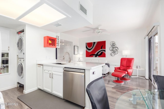 kitchen featuring stacked washer and dryer, visible vents, a sink, dishwasher, and a peninsula