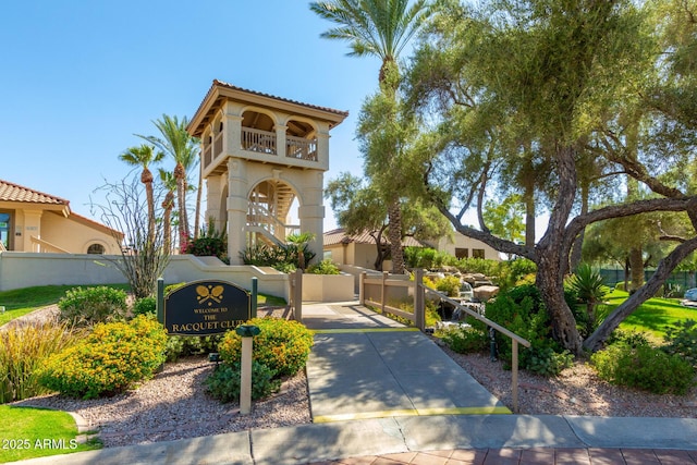 mediterranean / spanish house with a fenced front yard, a balcony, a tile roof, a gate, and stucco siding