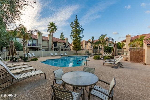 community pool with a patio area, fence, and a residential view