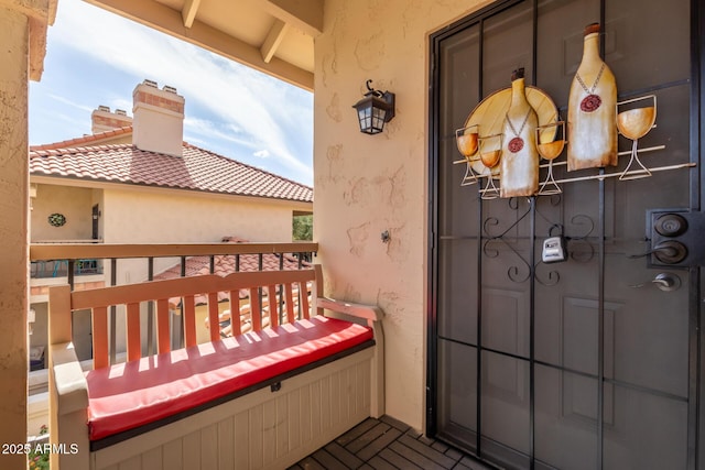 exterior space featuring a tiled roof, a chimney, a balcony, and stucco siding