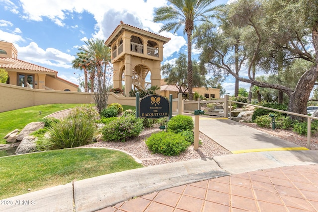 mediterranean / spanish home with a tile roof, fence, a gate, and stucco siding