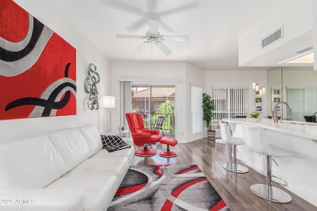 living room featuring a ceiling fan, baseboards, visible vents, and wood finished floors