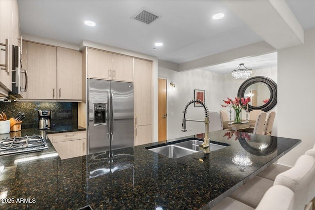 kitchen featuring sink, dark stone countertops, stainless steel fridge with ice dispenser, kitchen peninsula, and light brown cabinets