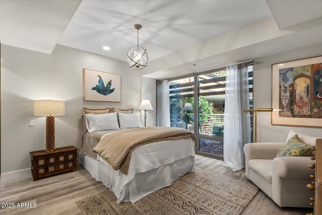 bedroom featuring light hardwood / wood-style flooring, access to outside, and an inviting chandelier