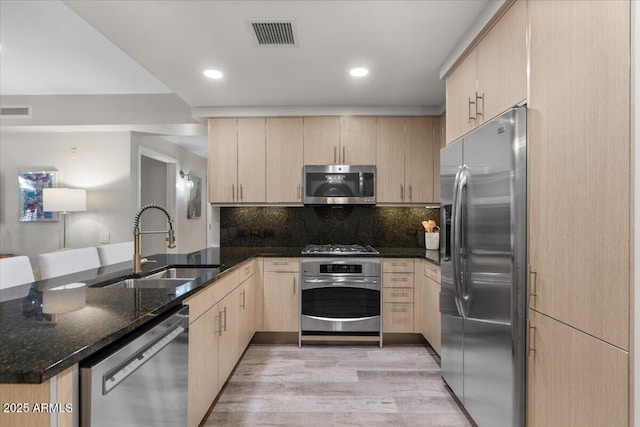 kitchen featuring appliances with stainless steel finishes, light brown cabinetry, and kitchen peninsula