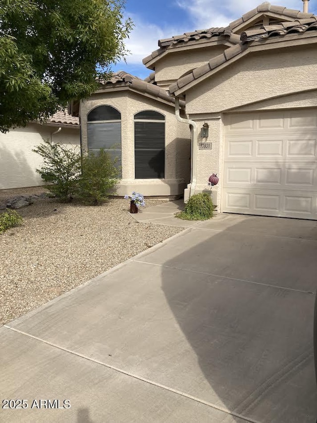 view of front of home featuring a garage, a tiled roof, and stucco siding