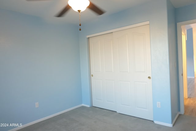 unfurnished bedroom featuring light carpet, a closet, and ceiling fan