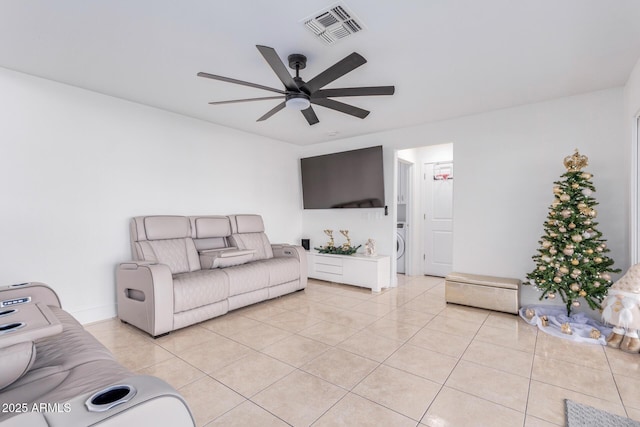 living room featuring washer / clothes dryer, ceiling fan, and light tile patterned flooring