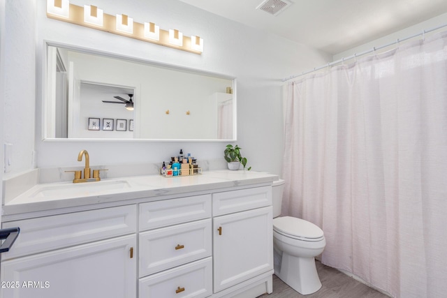 bathroom featuring ceiling fan, hardwood / wood-style floors, vanity, and toilet