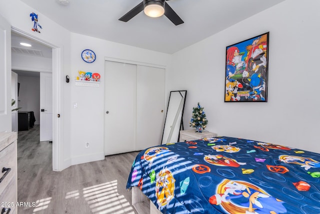 bedroom featuring ceiling fan, a closet, and light hardwood / wood-style flooring