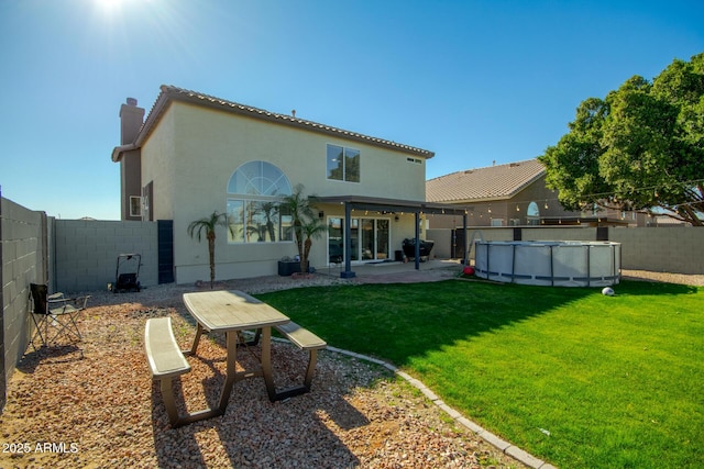 rear view of house with a patio area, a fenced in pool, and a yard