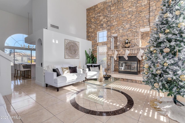 living room with a fireplace, a towering ceiling, and tile patterned floors