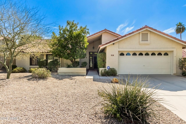 view of front of house with concrete driveway, an attached garage, a tile roof, and stucco siding