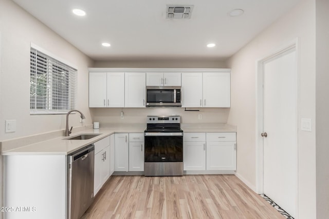 kitchen featuring visible vents, light countertops, white cabinets, stainless steel appliances, and a sink