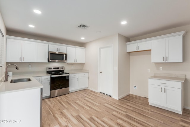 kitchen with visible vents, a sink, white cabinetry, appliances with stainless steel finishes, and light wood finished floors