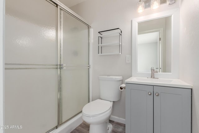 full bathroom featuring vanity, a shower stall, toilet, and wood finished floors