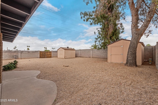 view of yard featuring a storage shed, a fenced backyard, and an outdoor structure