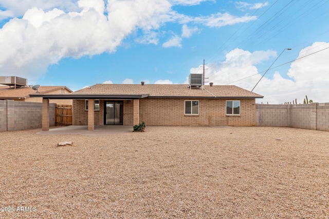 back of house featuring brick siding, roof with shingles, central AC unit, a fenced backyard, and a patio area