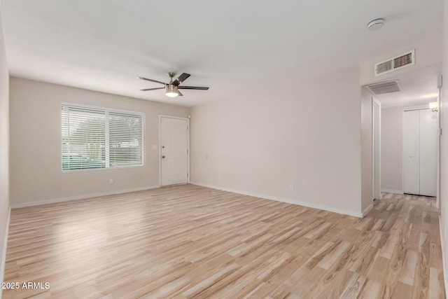 spare room with baseboards, a ceiling fan, visible vents, and light wood-type flooring