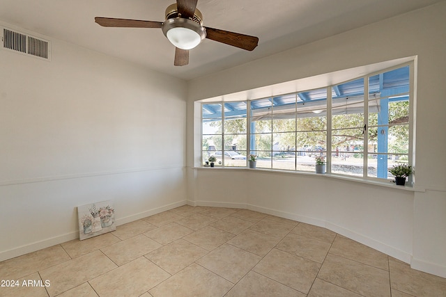 tiled empty room featuring a wealth of natural light and ceiling fan